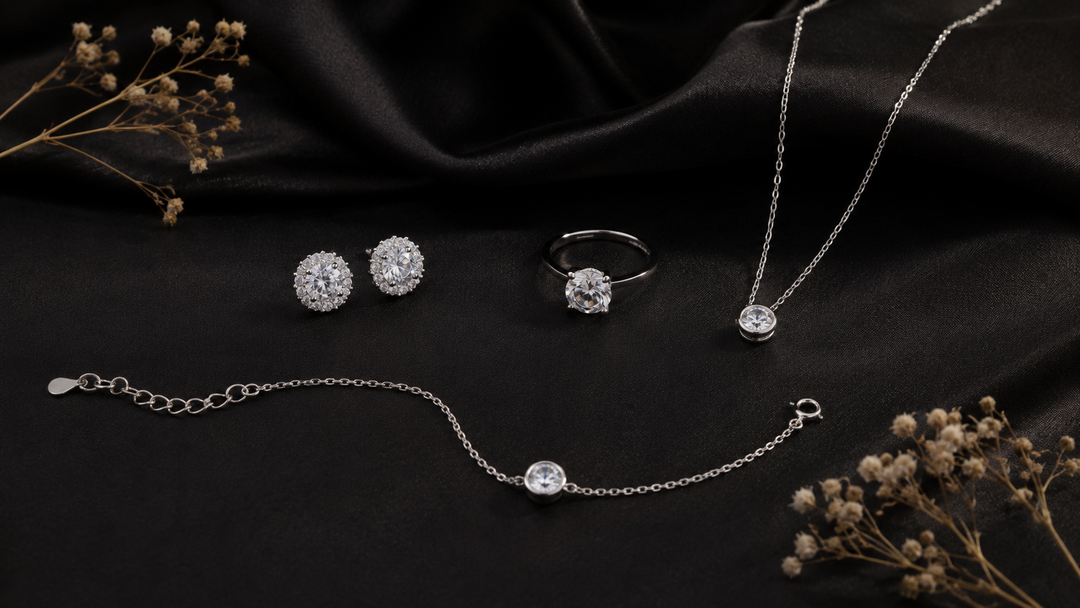 Koleksi perhiasan silver 925 DAVINA warna silver berupa anting, cincin, kalung, dan gelang dengan zirconia bening di atas kain satin hitam.