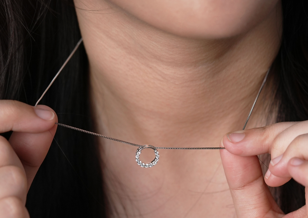 Close up wanita memegang kalung perak S925 DAVINA model cincin dengan detail zirconia, terlihat juga cincin silver di jari.