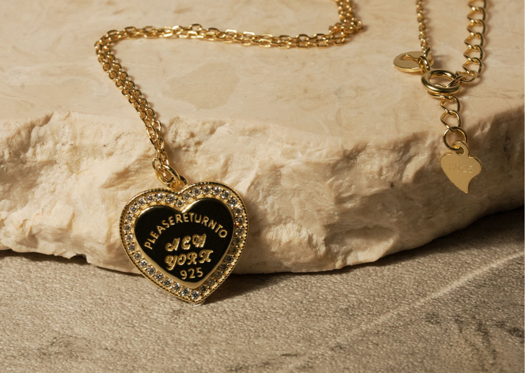 Kalung hati vintage berwarna gold dengan liontin berbentuk hati bertuliskan 'Please Return To New York 925', dikelilingi zirconia berkilau dari koleksi DAVINA.